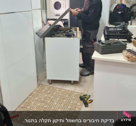 טכנאי עובד על מכשיר חשמלי במטבח עם כלים מסביב